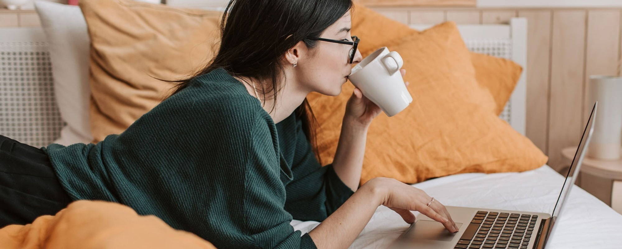 Person drinking from a mug while using laptop